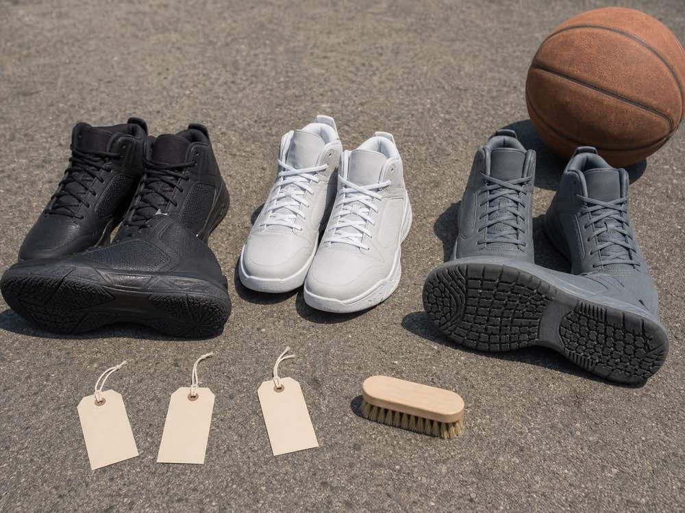 Three unbranded durable basketball shoe pairs with deep rubber tread on rough concrete
