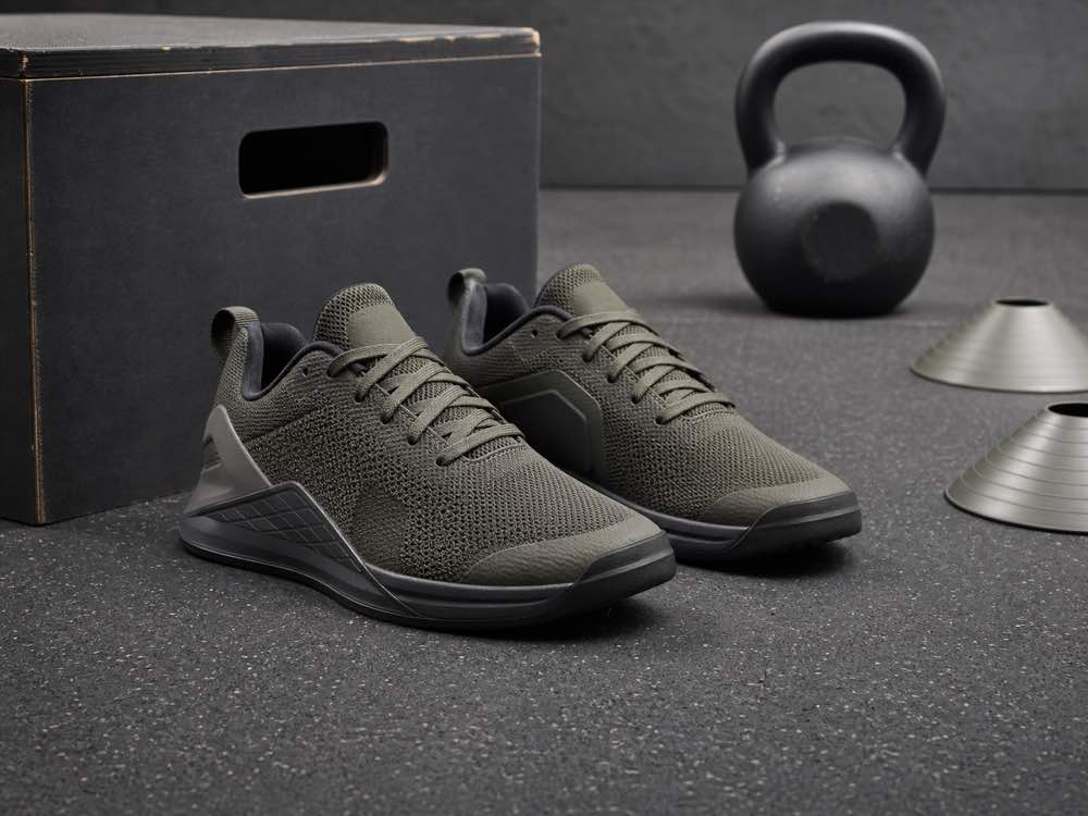 Unbranded low stable cross-training shoes on gym flooring beside a plyometric box and kettlebell